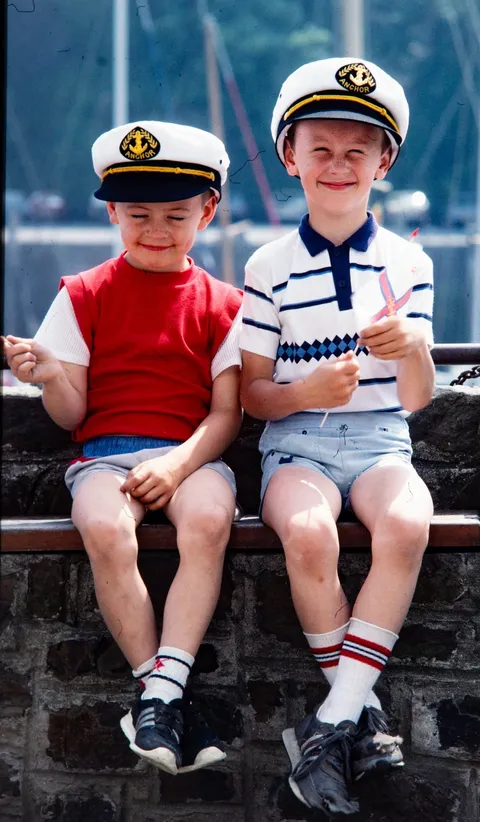 Restored slide of two young boys in sailor caps sitting on a harbour wall